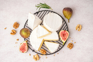 Grid with pieces of tasty Camembert cheese on light background