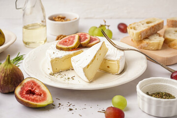 Plate with pieces of tasty Camembert cheese on grey background