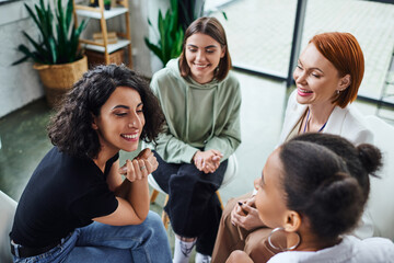 high angle view of cheerful multiracial woman talking to african american girlfriend near smiling...