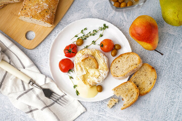 Plate of tasty baked Camembert cheese on light background