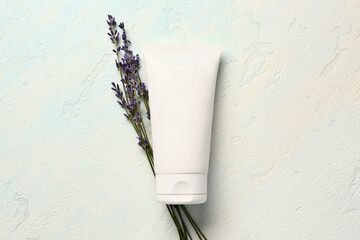 Tube of cosmetic product and lavender flowers on light background