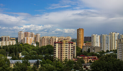 Fototapeta na wymiar Cityscape - panoramic top view of a residential quarter with modern high-rise buildings with green trees on a sunny summer day and blue sky with white clouds in Reutov, Moscow region and copy space