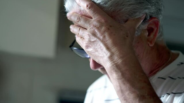 Preoccupied senior man feeling nervous reading content. Candid close-up face of an elderly gray hair person feeling exasperated