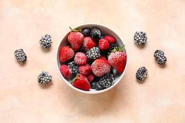 Bowl of frozen berries on beige grunge background