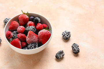 Bowl of frozen berries on beige grunge background