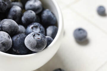 Bowl of frozen blueberry on white tile background