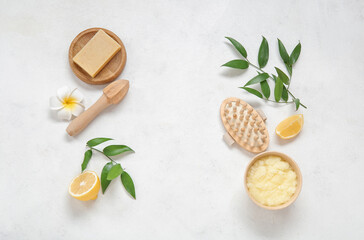 Fototapeta na wymiar Bowl of lemon body scrub with massage brush, juicer and soap on white background