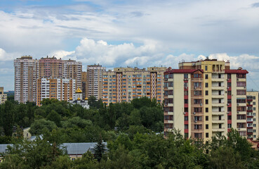 Cityscape - panoramic top view of the city with modern multi-storey buildings and green trees on a cloudy summer day and space to copy