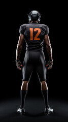 Fototapeta na wymiar rear view of american football athlete in blue uniform standing in front of black background. Full body shoot. nfl sports image concept.