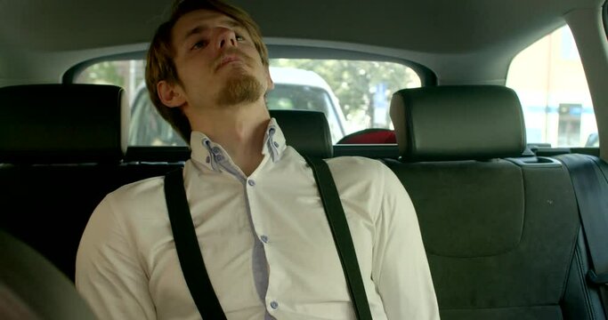 A man in suspenders sits on the seat of a car with his hands tied behind his back. He understands that he is limited in space. Reconciliation with the situation, car interior.