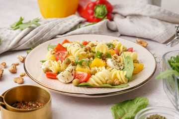 Plate of tasty pasta salad with pepper and peas on white background