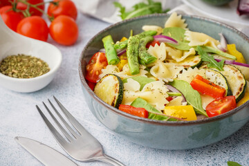 Bowl of tasty pasta salad with pepper and tomatoes on white background