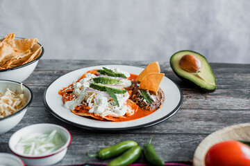 Mexican chilaquiles food with spicy red sauce, chicken and avocado traditional breakfast in Mexico Latin America