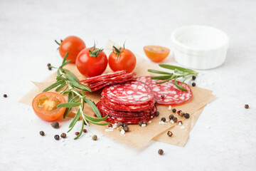 Slices of tasty salami on light background