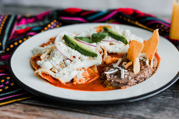 Mexican chilaquiles food with spicy red sauce, chicken and avocado traditional breakfast in Mexico Latin America