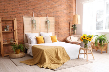 Vase with beautiful sunflowers on wicker chair in interior of stylish bedroom