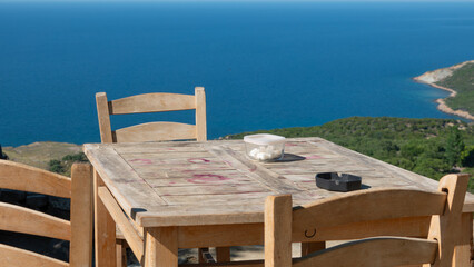 Gokceada (Imbros) coastline and a cute village tea garden view with wooden chairs and table. Tepeköy village, Çınaraltı-Pinarbasi location, Aegean Turkey