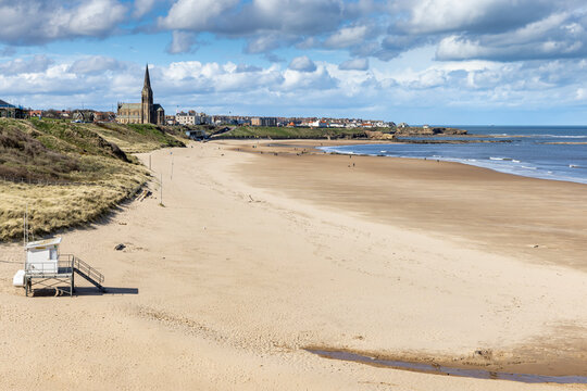 Long Sands beach at Tynemouth on a bright spring day, with St George's church at Cullercoats in the distance, Tyne and Wear, England, Uk
