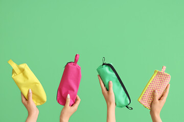 Female hands with pencil cases on green background