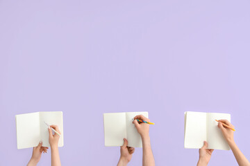 Hands writing in open notebooks on lilac background
