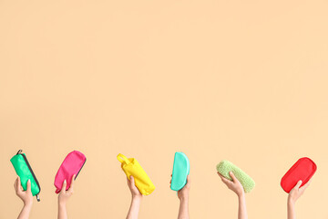 Hands with pencil cases on beige background