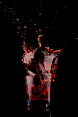 splash in red negroni drink with campari and vermouth on black background