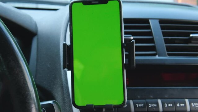 Mobile phone on the car air vent.Blank with green screen.Mock up smart phone in car.
