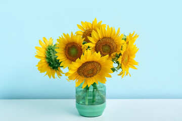Vase with sunflowers on shelf near blue wall © Pixel-Shot