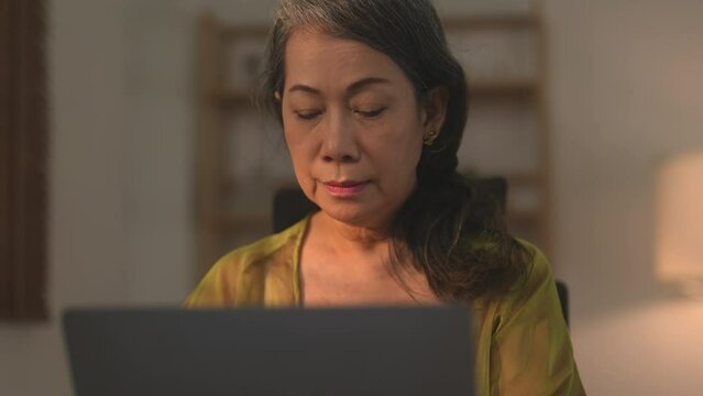 Asian female senior entrepreneur using her laptop at home.