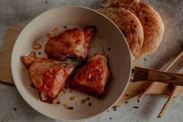Frying pan with fried chicken fillet on a gray background