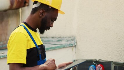 Expert repairman doing inspection of refrigerant levels and necessary repairs to prevent major breakdowns. Professional worker troubleshooting condenser, writing findings on clipboard