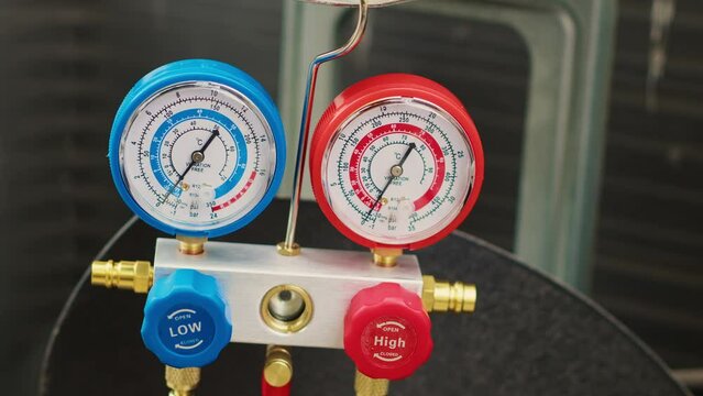 Close up shot of pressure measurement device used for checking condenser freon pressure. Set of manifold indicators showing high or low refrigerant levels in outdoor air conditioner
