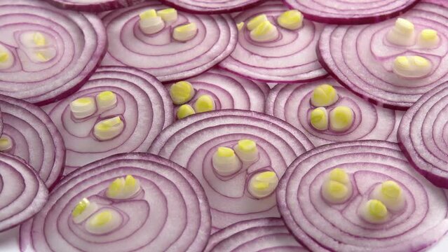 Sliced red onion rotates as background for cooking show, restaurant or food video. Sliced shallot rings close-up. Top view of food healthy background with vegetable of rich vitamin