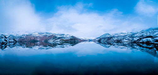 snowy mountains and blue sky with reflection in lake shot in winter season