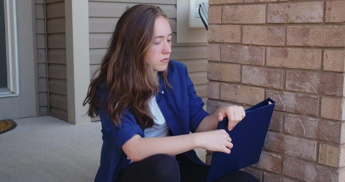 Sad Student Sitting on Steps Outside of a Suburban House
