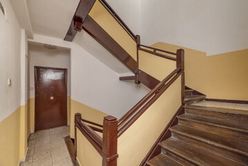 Flights of old stairs with brown wooden railings and steps and dark cream