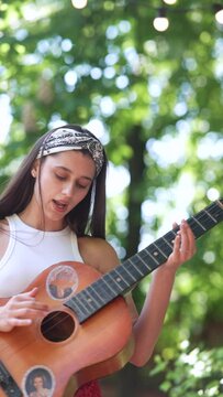 close up portrait of The beautiful hippie girl is singing a song and playing the guitar 