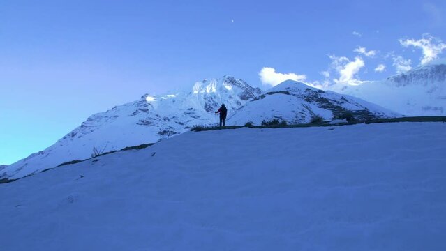 Aerial revealing view hiker at the top of mountain enjoy views reaching destination summit. Outdoor adventure sports in winter alpine Himalayas.Annapurna circuit trek. Tilicho camp