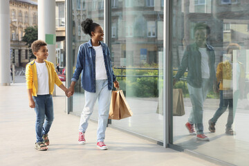 Fototapeta premium Family shopping. Happy mother and son with purchases near mall outdoors