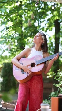 close up portrait of The beautiful hippie girl is singing a song and playing the guitar 