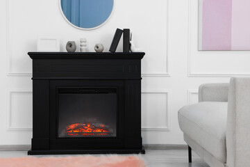 Black stylish fireplace near comfortable sofa in cosy living room