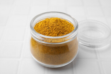 Jar with curry powder on white table, closeup