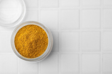 Jar with curry powder on white tiled table, top view. Space for text