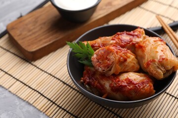 Delicious stuffed cabbage rolls cooked with tomato sauce on grey table, closeup. Space for text