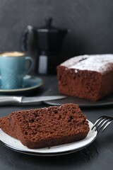 Pieces of tasty chocolate sponge cake on black table. Space for text