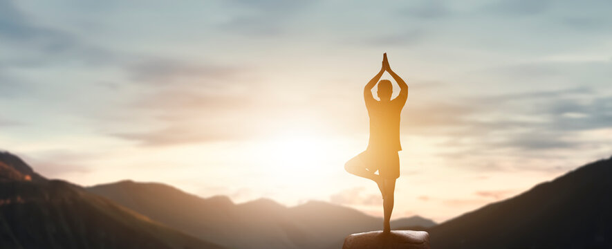 man doing yoga pose on the top of the mountain - peace, relaxation and mental health concept