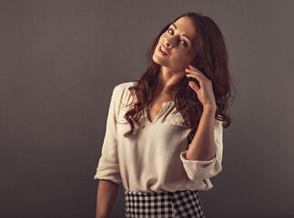Beautiful flirting happy woman with long brown healthy hair style in white shirt and skirt fashion clothing. Closeup studio portrait with empty copy space. Toned