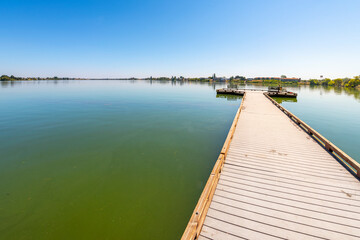 Obraz premium A man fishes off a pier at the 24 acre lakeside Blue Heron Park in the city of Moses Lake, Washington, in Central Washington, USA.