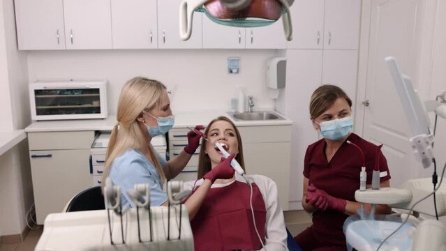 Oral examination, dental expertise, dental care. Skilled dentist is making detailed examination of young woman's oral cavity using intraoral camera.