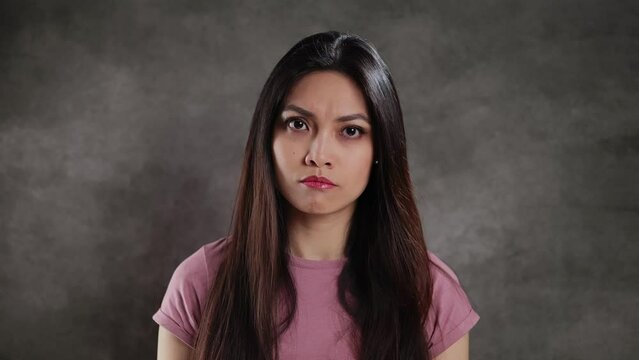 Young Asian woman in a studio looks irritated - extreme slow motion